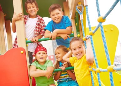 Smiling children playing on colorful playground equipment