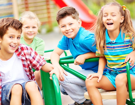 Smiling children playing on playground merry-go-round