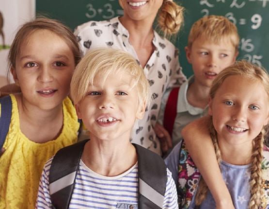 Smiling elementary students with teacher in classroom