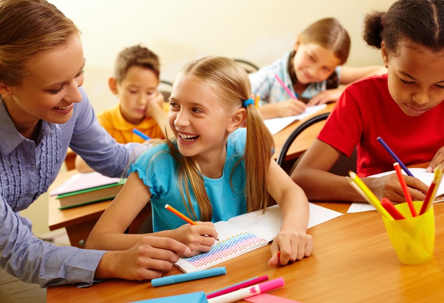 Teacher helping elementary students in classroom