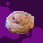 A pink frosted donut with colorful sprinkles on a purple background.