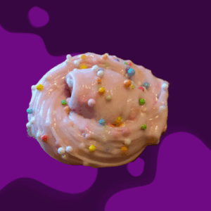 A pink frosted donut with colorful sprinkles on a purple background.