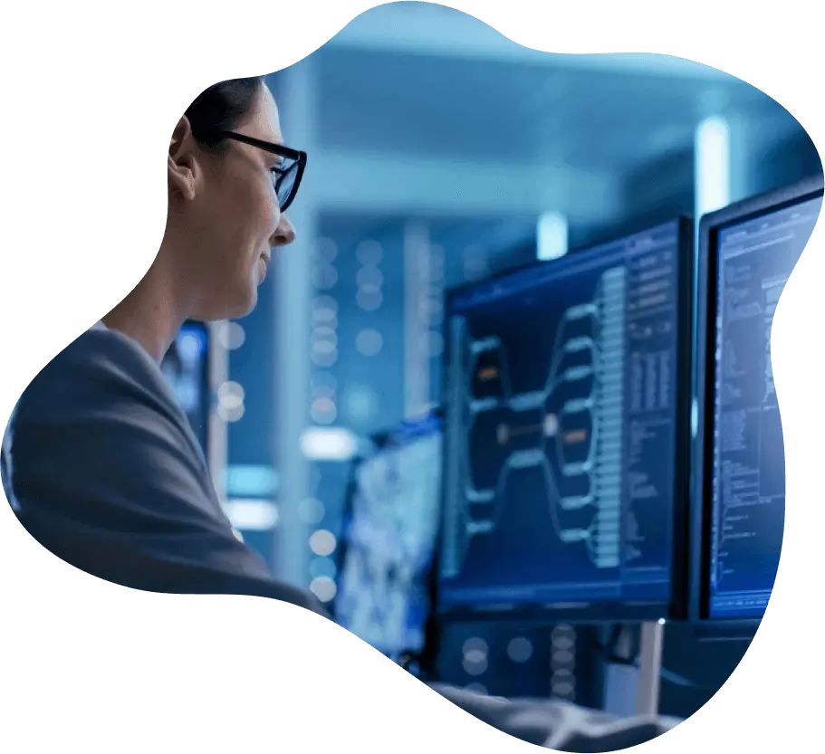 Woman analyzing data on multiple computer screens in a tech environment.