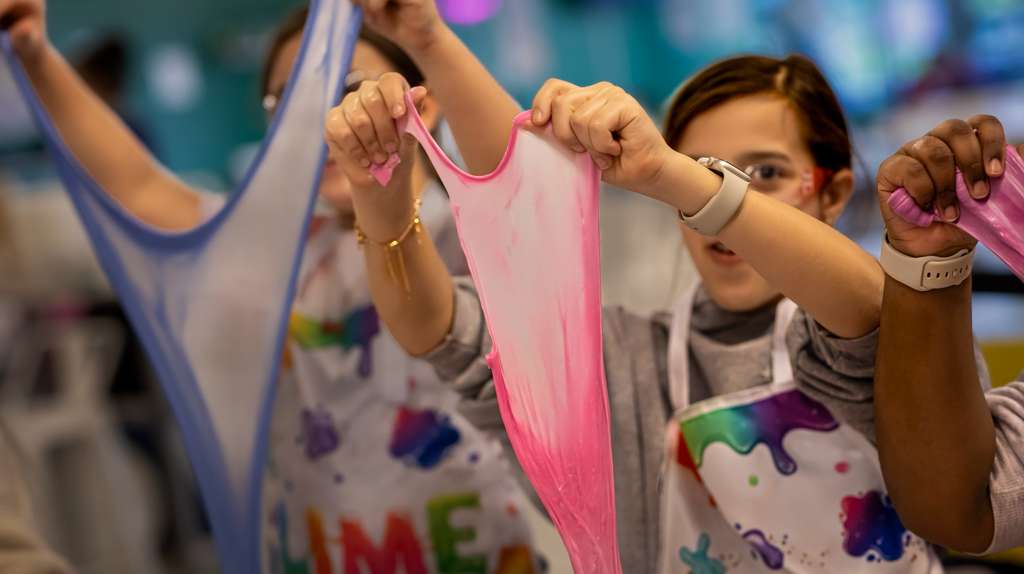 Kids stretching pink slime in art class