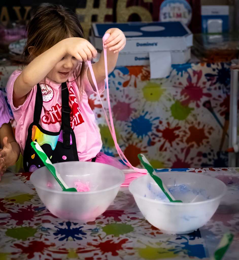 Girl stretching pink slime over bowls