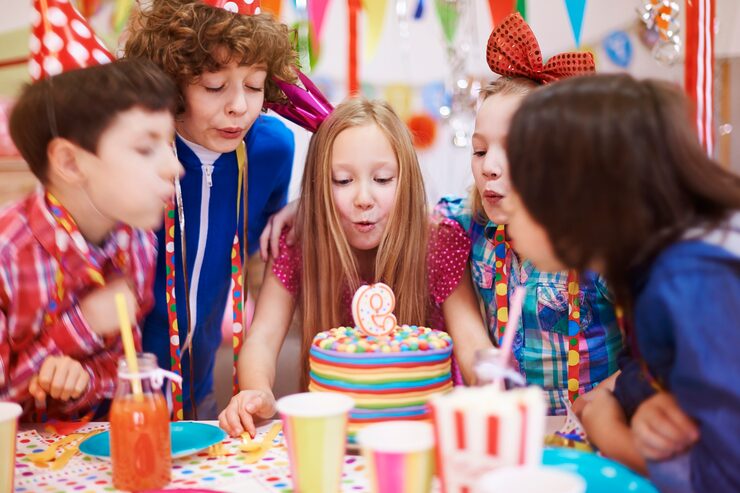 Children blowing out candles at birthday party
