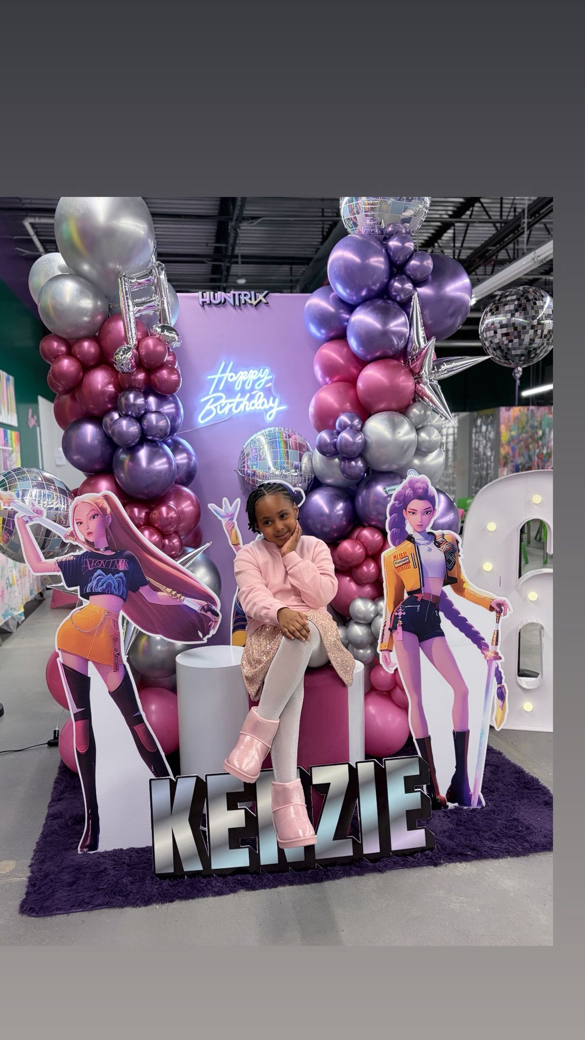 Girl posing at purple balloon birthday display